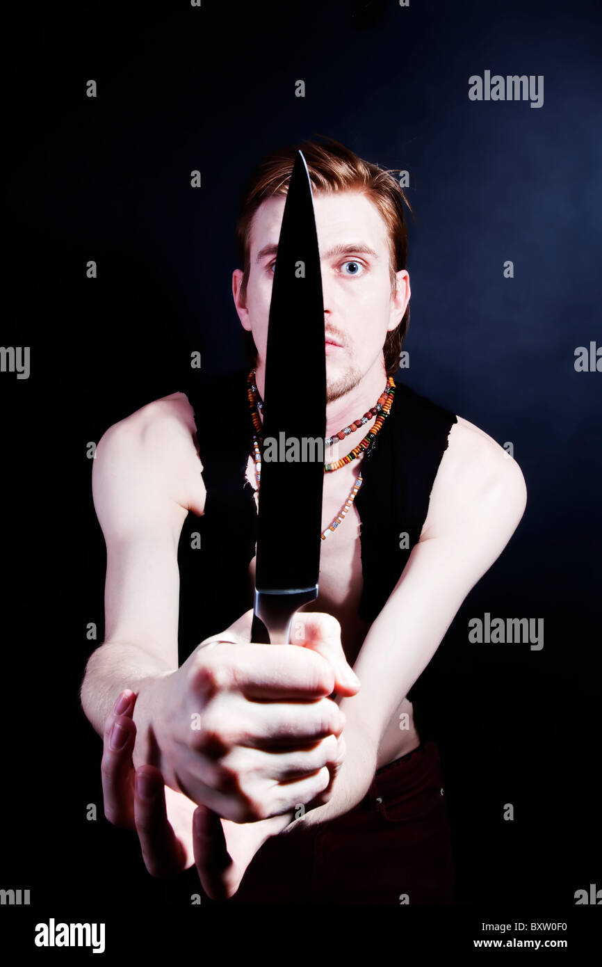 junger Mann mit Messer auf schwarzem Hintergrund Stockfoto