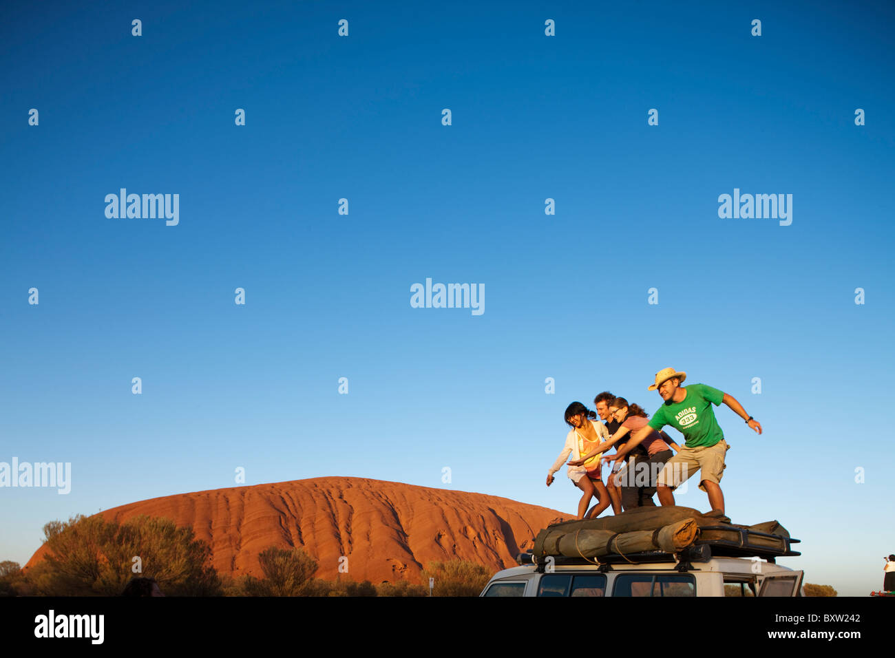 Australien-Northern Territory Uluru - Kata Tjuta National Park junge Touristen Pose für Schnappschüsse wie steigende Sonne leuchten Ayers Rock Stockfoto