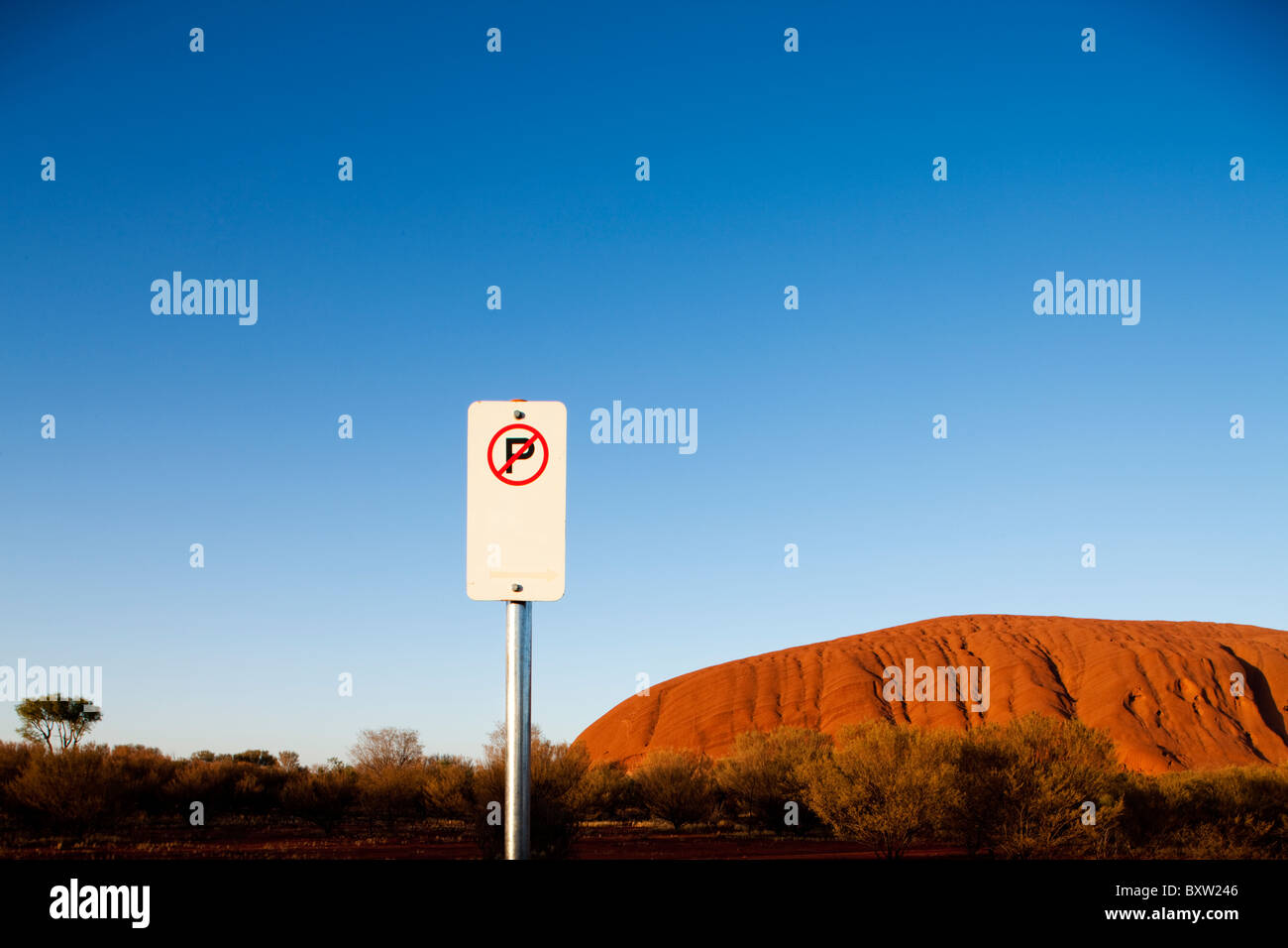 Australien-Northern Territory Uluru - Kata Tjuta National Park Rising Sun leuchtet No Parking Schild vor Ayers Rock mit Stockfoto