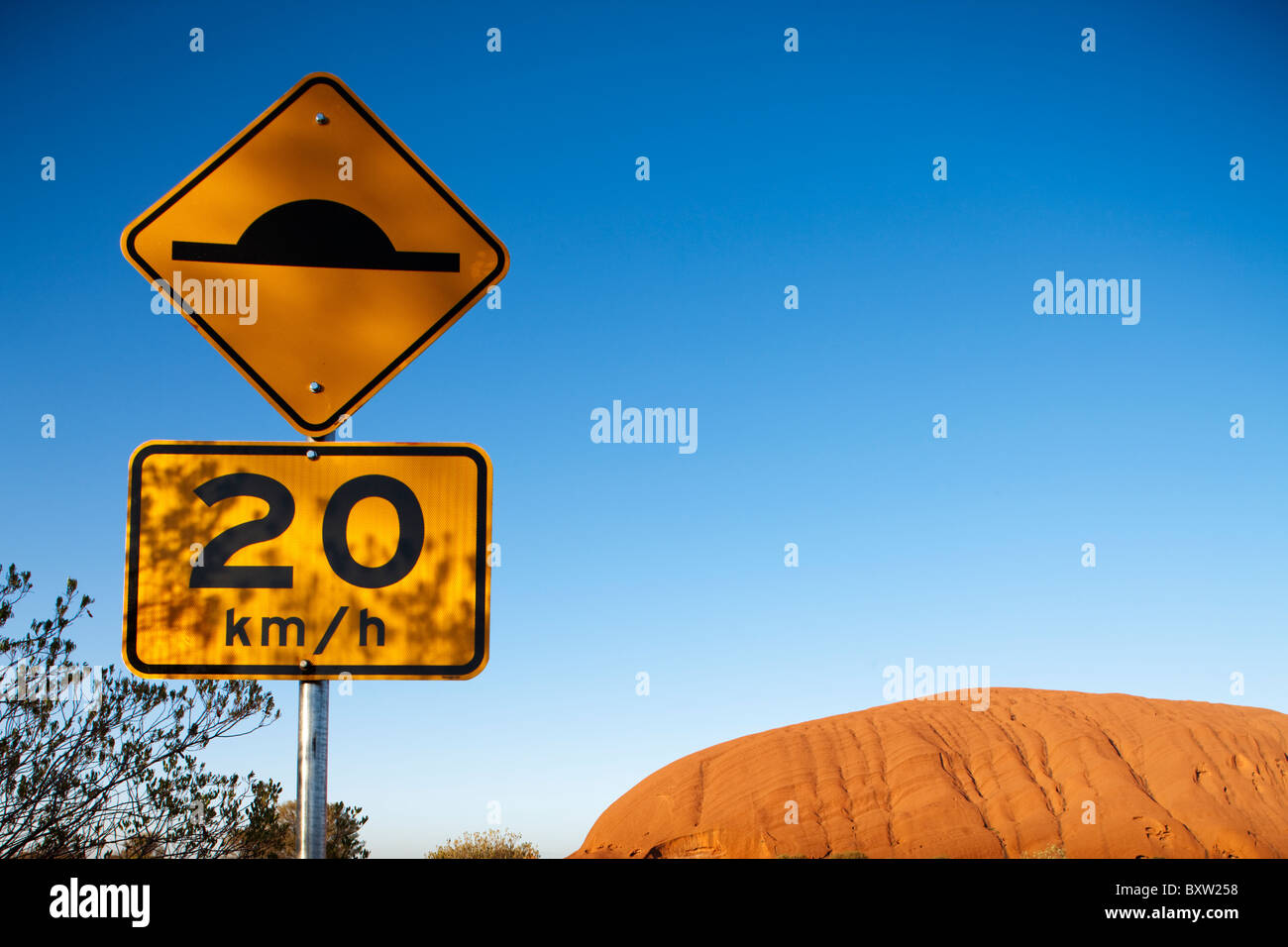 Australien-Northern Territory Uluru - Kata Tjuta National Park Speed Bump Warnschild vor der Ayers Rock am Sommermorgen Stockfoto