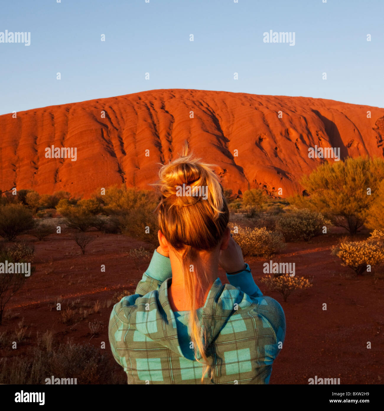 Australien-Northern Territory Uluru - Kata Tjuta National Park junge Frau nimmt Schnappschüsse bei Sonnenaufgang des Ayers Rock im Sommer Stockfoto