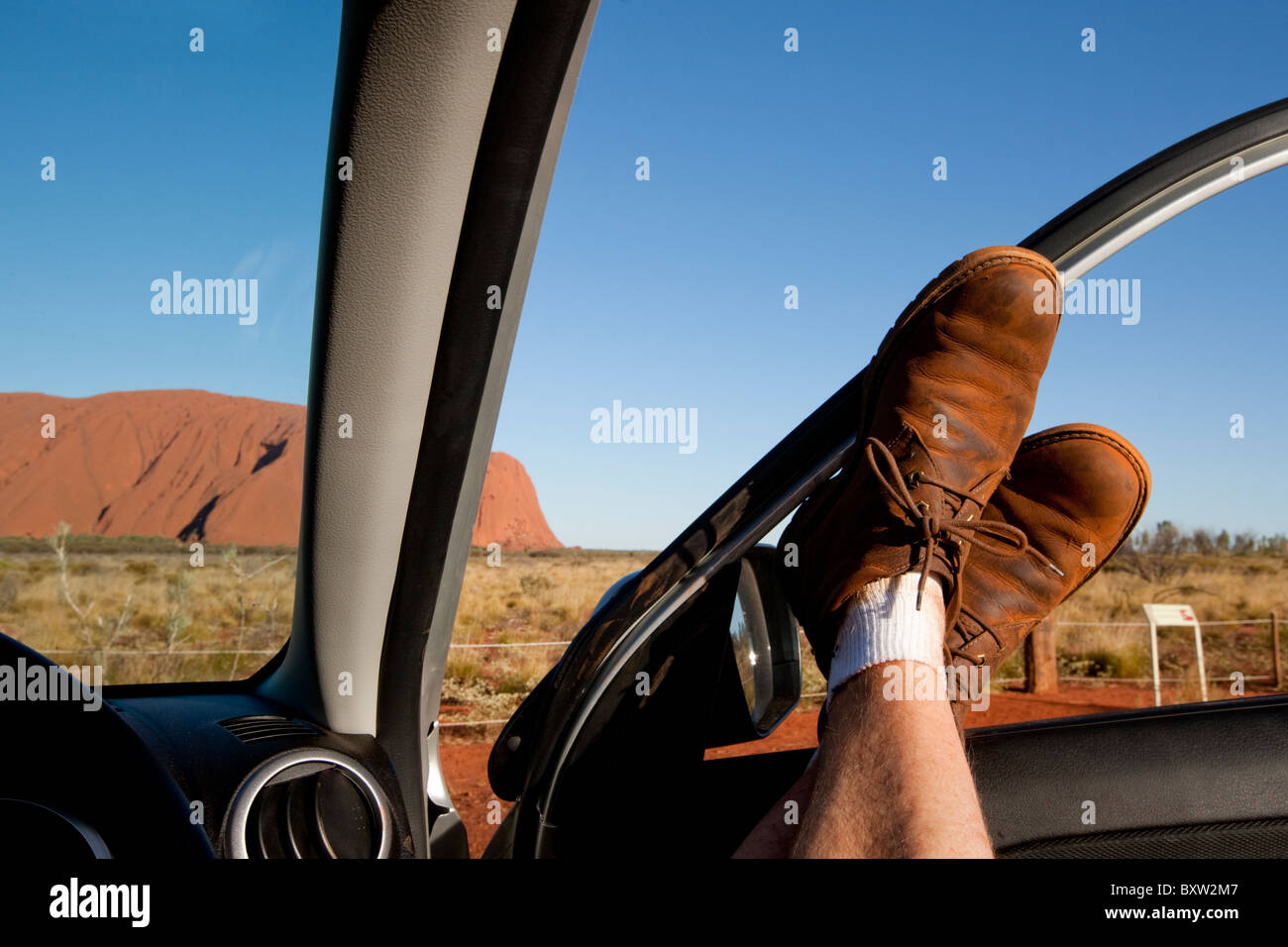 Australien-Northern Territory Uluru - Kata Tjuta National Park Tourist entspannt mit Stiefeln in Mietwagen in Nachmittagshitze am Stockfoto
