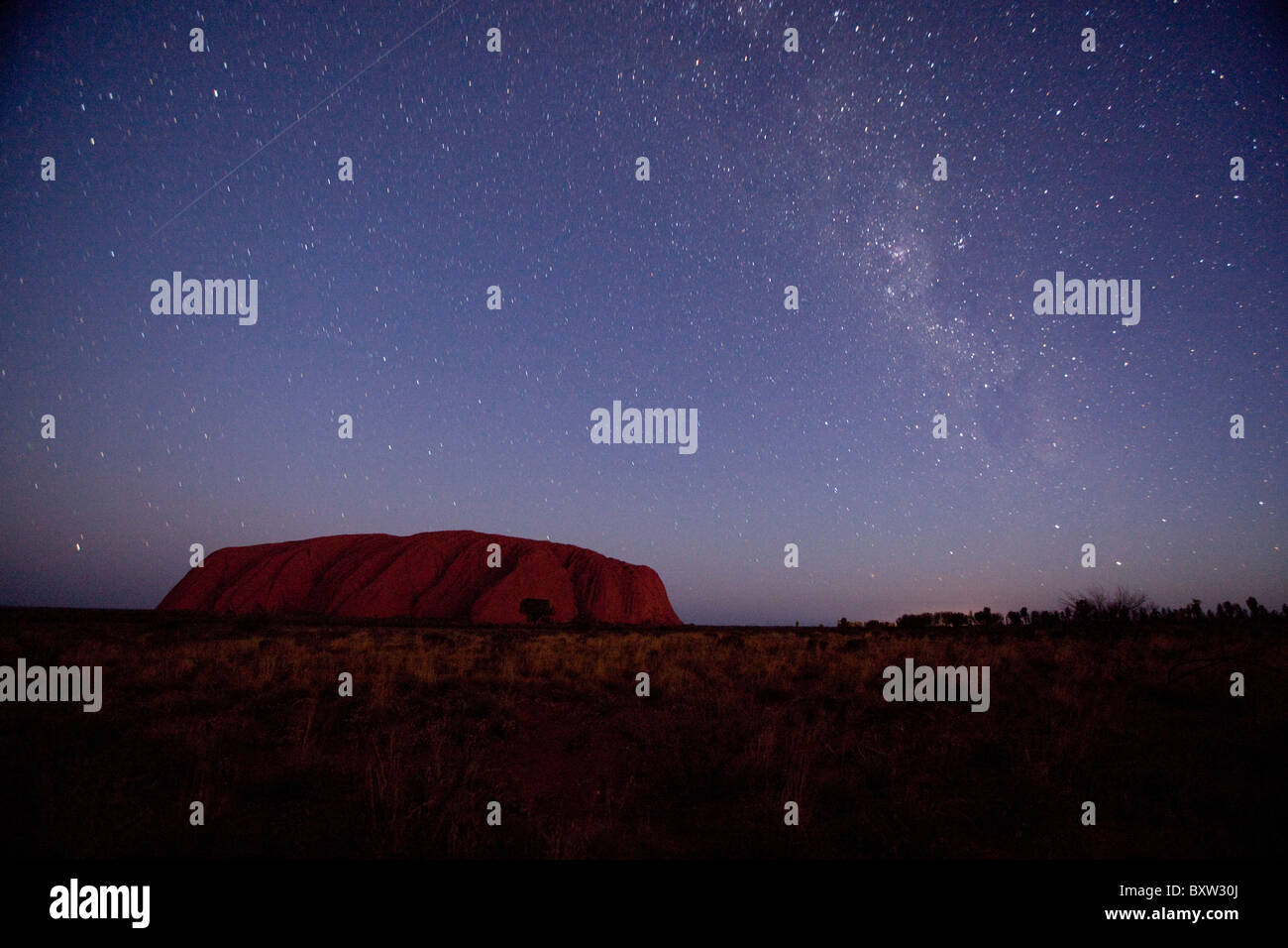 Australien, Northern Territory, Uluru - Kata Tjuta National Park, Sterne Kreis über Ayers Rock in der Abenddämmerung am Sommerabend Stockfoto