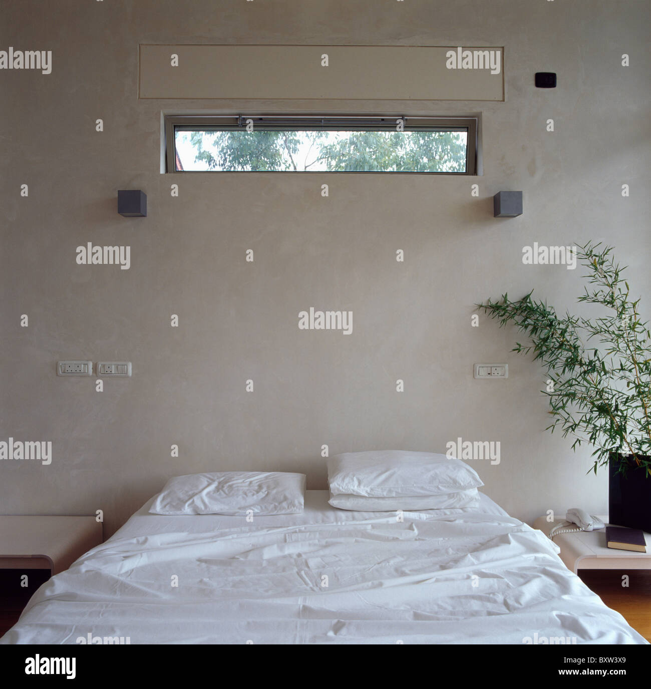 Schmale Fenster über Bett mit weißen Bettwäsche in modernen weiße Schlafzimmer Stockfoto