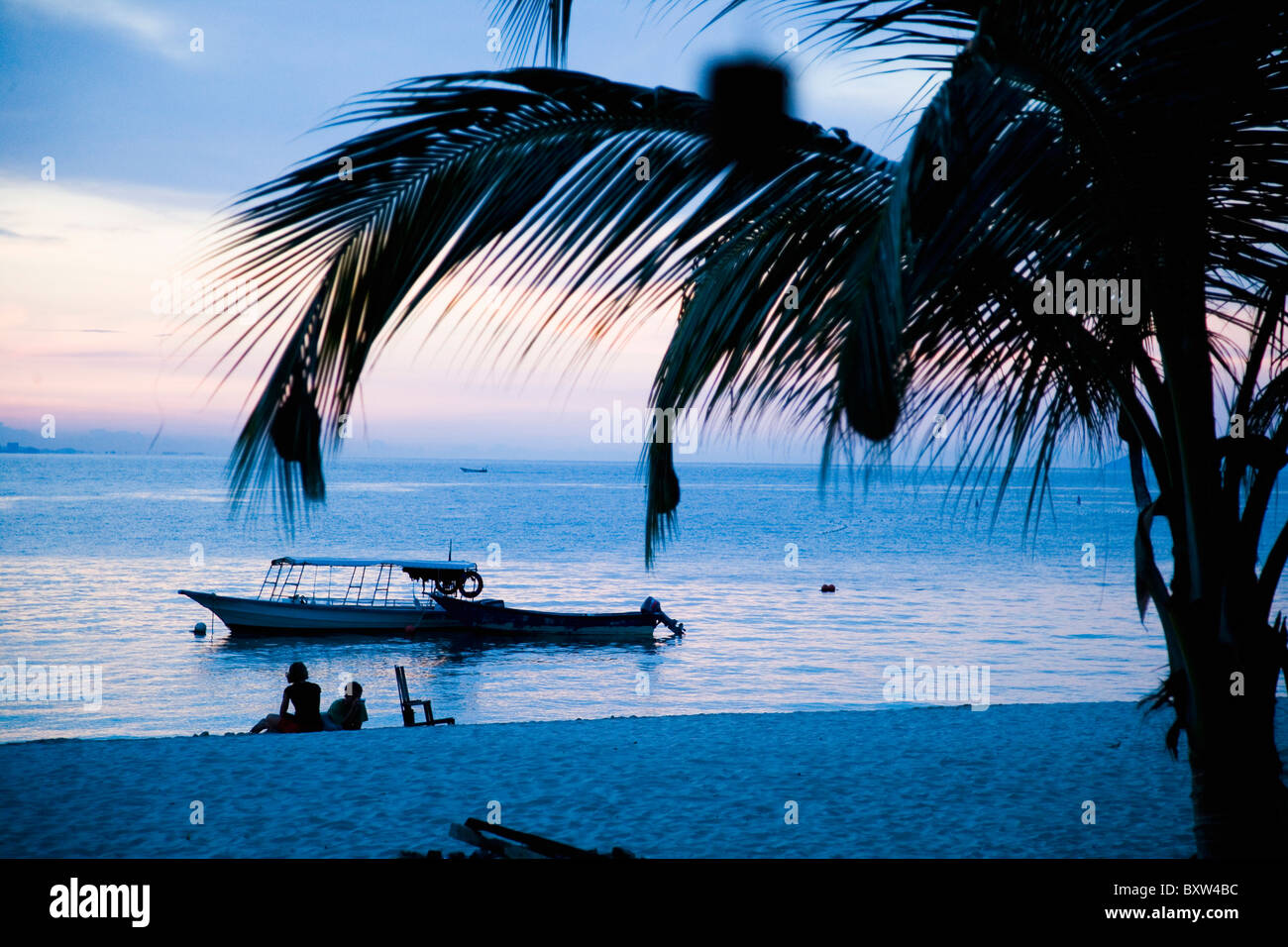 Silhouetten von Menschen entspannen am Strand in der Abenddämmerung Stockfoto