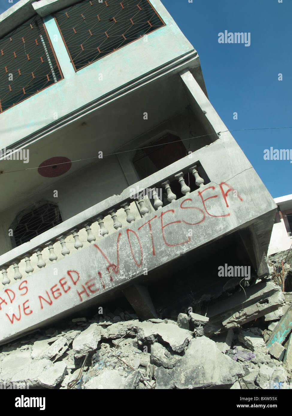 Erdbeben beschädigt Gebäude kippt etwa 30 Grad von der vertikalen. Sprühen Sie gemalte Zeichen "Wir brauchen Hilfe." Port-au-Prince, Haiti. Stockfoto