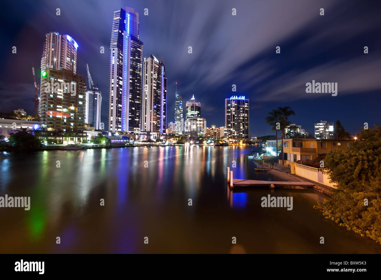 moderne Stadt in der Nacht mit sich bewegenden Wolken und Pier im Vordergrund Stockfoto