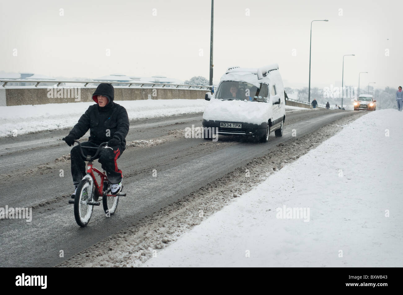 Radfahrer auf der Itchen Brücke auf einer verschneiten Straße. Stockfoto