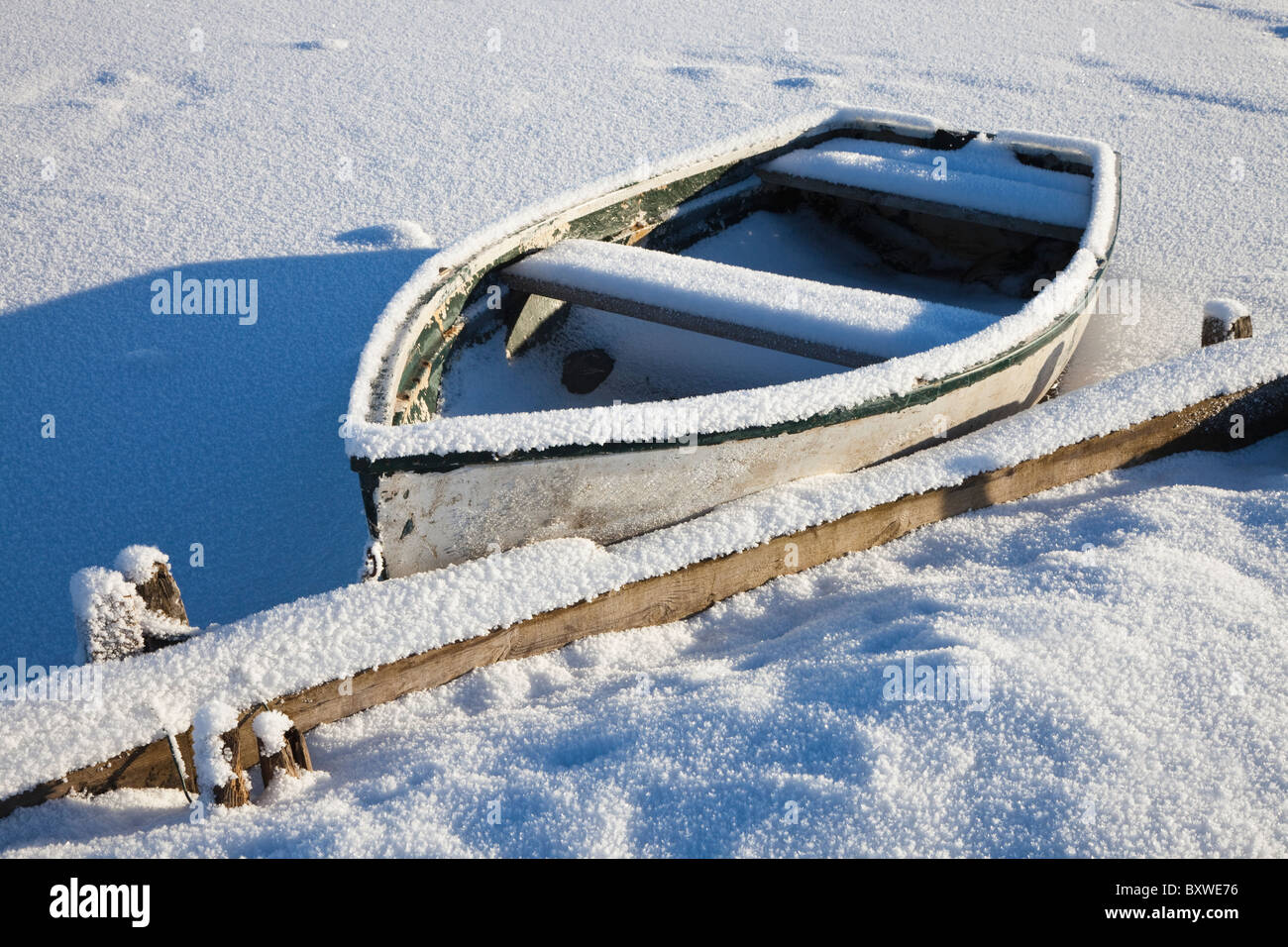 Kleines Ruderboot, bedeckt mit Schnee und Raureif am Rand von einem Bootfahren Teich, Schottland Stockfoto