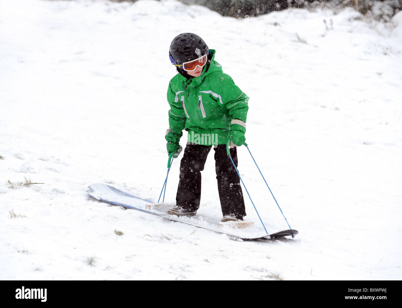 Kleiner Junge Snowboarden zu lernen Stockfoto