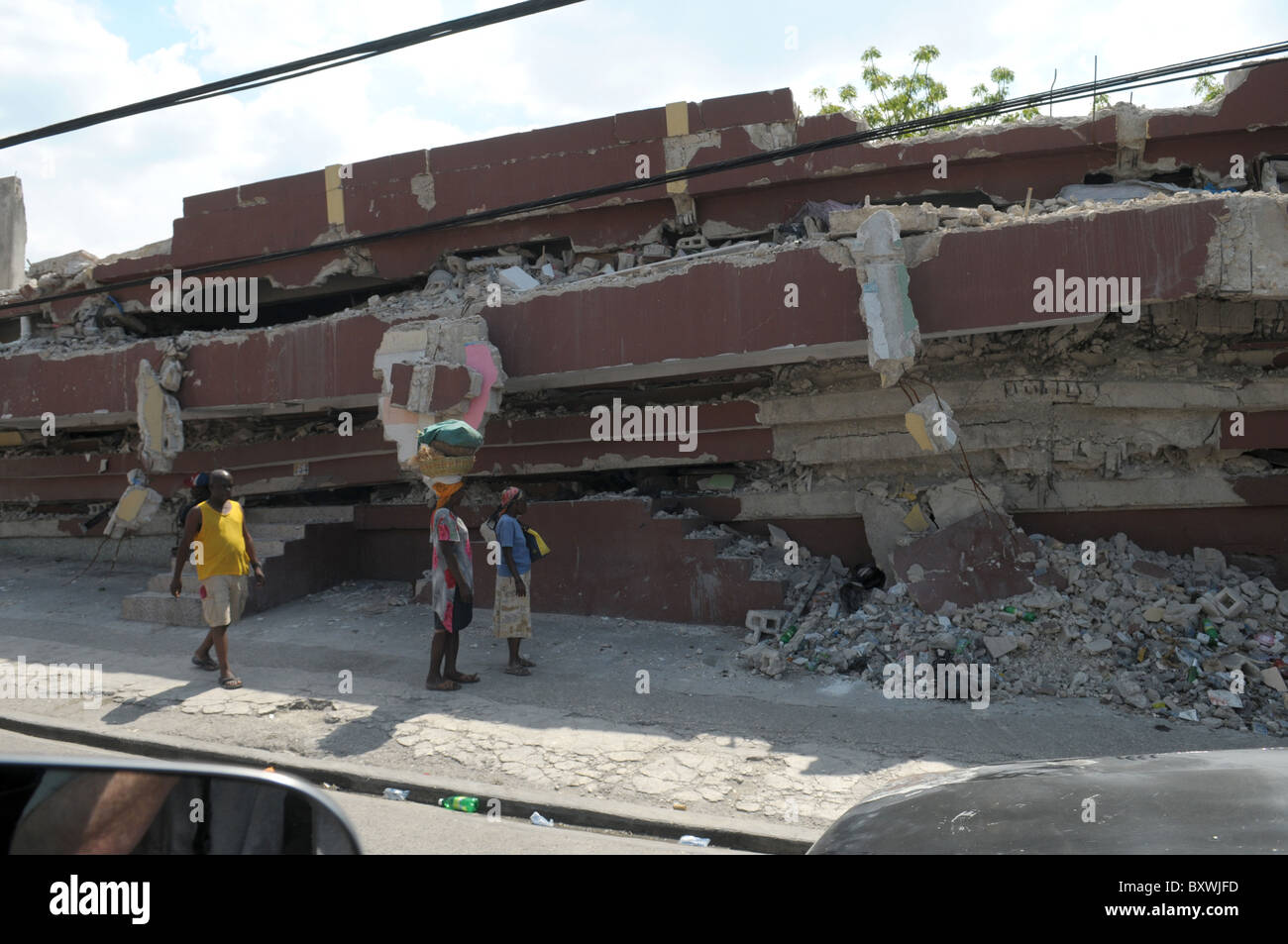 Drei Menschen gehen vorbei an einem zerstörten Gebäude im zentralen Port au Prince nach dem Erdbeben in Haiti Stockfoto