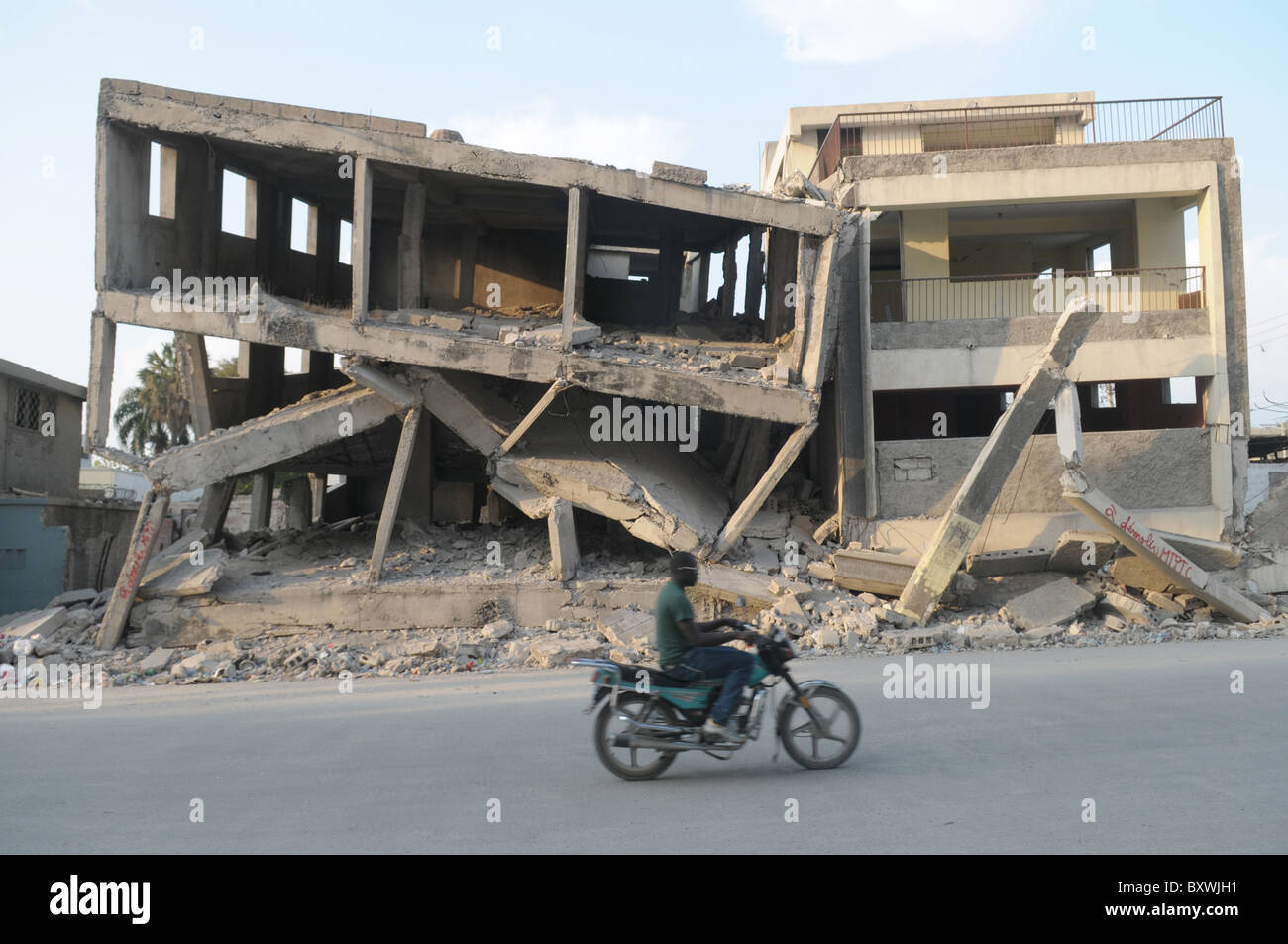 Motorradfahrer übergibt Gebäude verwüstet in zentralen Port-au-Prince nach dem Erdbeben in Haiti 2010 Stockfoto
