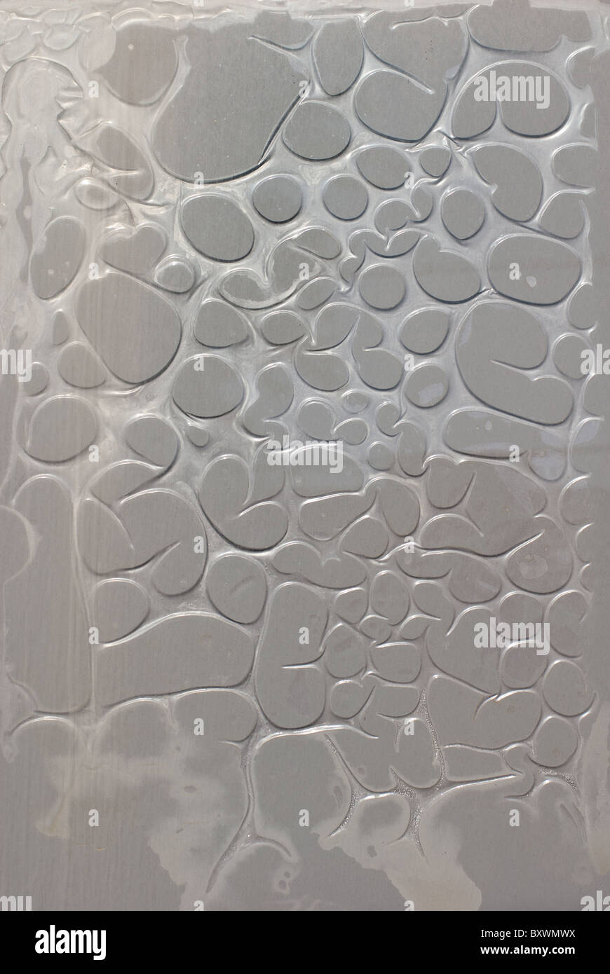 sprudelnde grauen Kunststoff-Folie auf einer Glasoberfläche Stockfoto