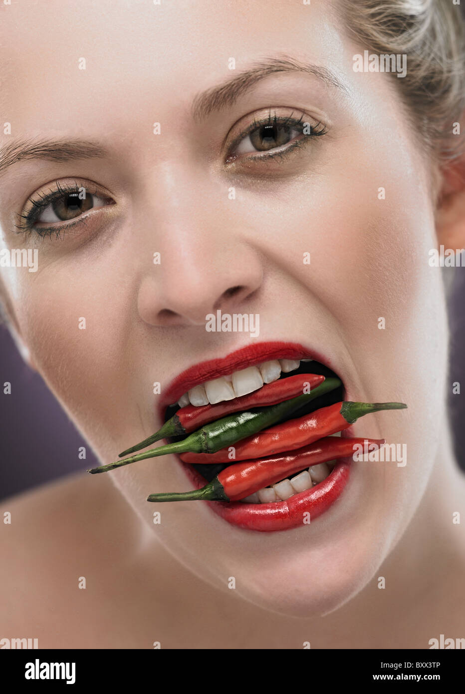 weiße blonde Frau mit Chili in den Mund Stockfoto