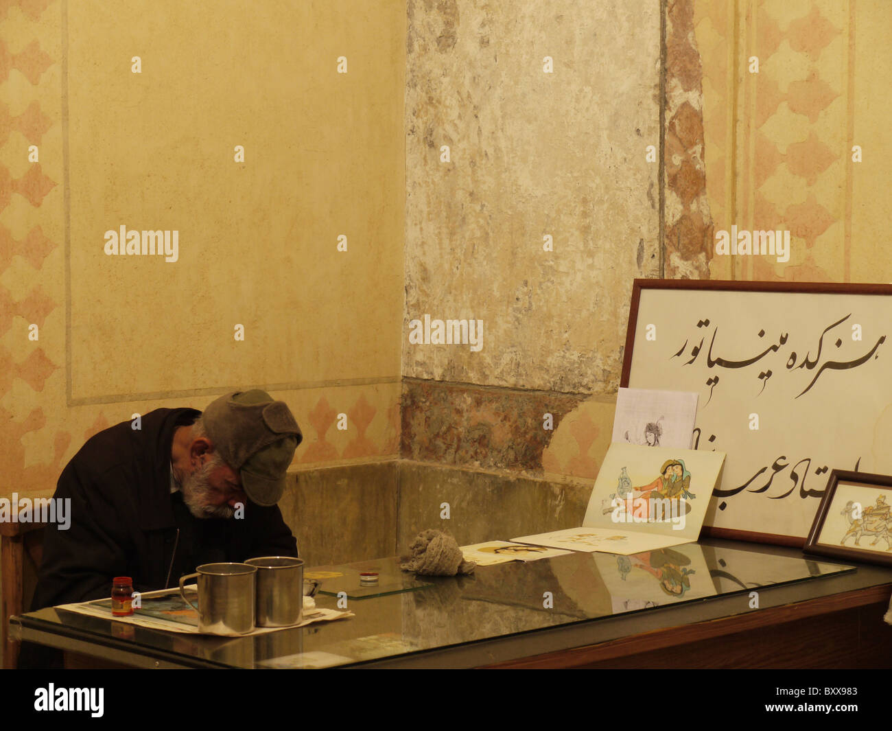 Mann schläft auf seinem Schreibtisch in einem umgebauten Raum Hamman-e Vakil, Shiraz, Iran Stockfoto