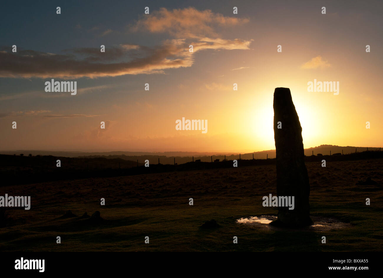 Stehender Stein Silhouette gegen die untergehende Sonne am Merrivale, Dartmoor, Devon UK Stockfoto