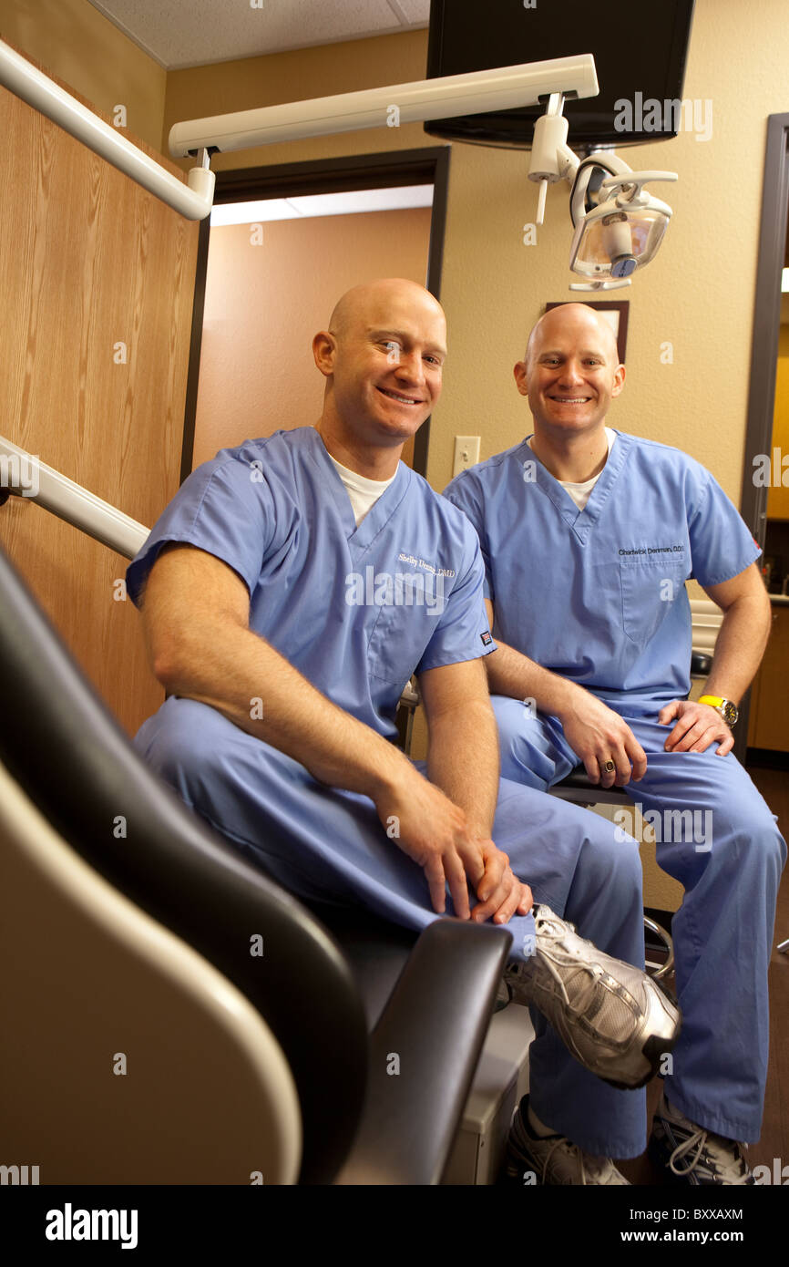Zahnärzte, die eineiigen Zwillinge sind stellen in einem Untersuchungsrichter Raum in der Klinik, wo sie zusammen in Austin, Texas USA ausüben Stockfoto