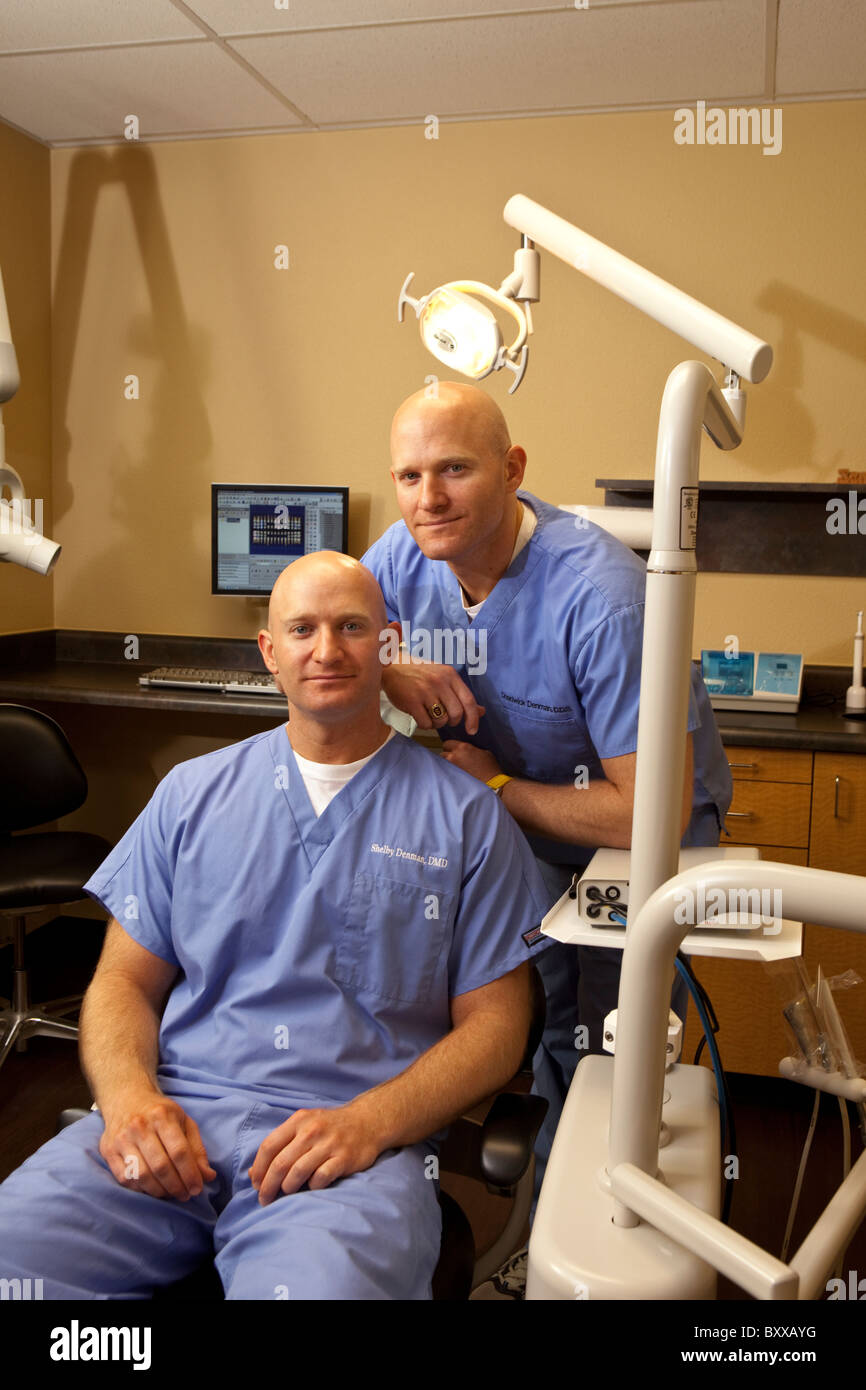 Zahnärzte, die eineiigen Zwillinge sind stellen in einem Behandlungsraum in der Klinik, wo sie zusammen in Austin, Texas USA ausüben. Stockfoto
