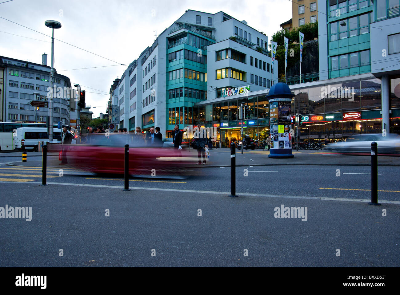 Fußgänger warten, wie Autos in Bewegung Geschwindigkeit um große Verkehrsinsel in der Altstadt Luzern Schweiz Einkaufsviertel verwischen Stockfoto