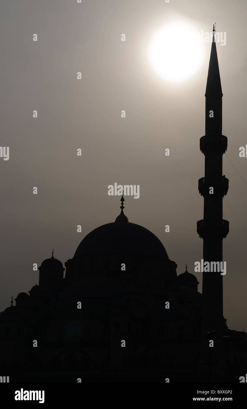 Süleymaniye Moschee Silhouette Istanbul Türkei // ISTANBUL, Türkei — Silhouette der Süleymaniye Camii (Süleymaniye Moschee) in Istanbul, Türkei. Die Sonne erzeugt ein dramatisches Hintergrundlicht, das die ikonische Kuppel und das Minarett vor dem trüben Himmel hervorhebt. Stockfoto