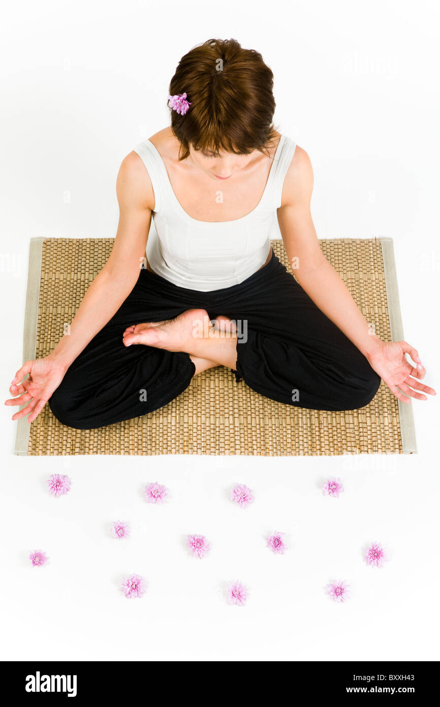 Ansicht von oben der hübsche Frau auf dem Boden sitzend und doing Yoga Übung mit rosa Blüten vor ihr Stockfoto