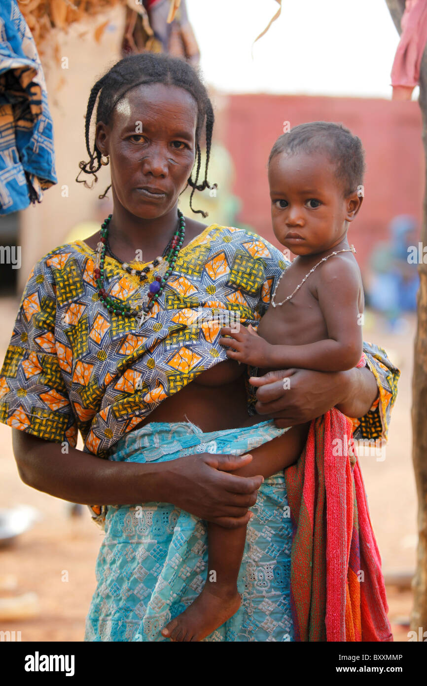 Eine Fulbe-Frau hält ihr Kind in ihrem Haus in Djibo im nördlichen Burkina Faso, Westafrika. Stockfoto