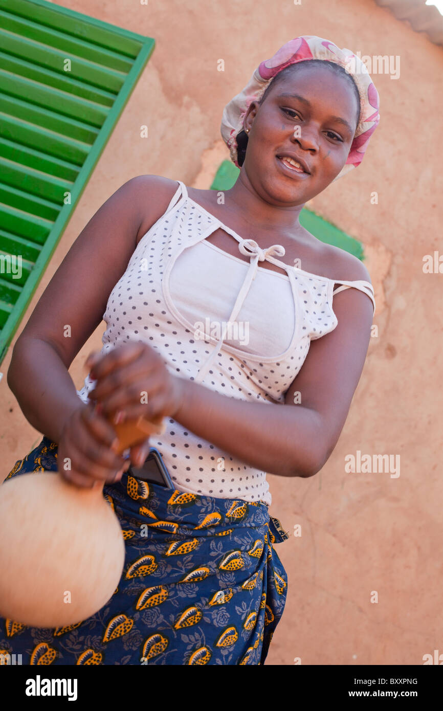 Eine junge Fulbe-Frau in der Stadt Djibo im nördlichen Burkina Faso schüttelt einen Kürbis mit frischer Milch. Stockfoto