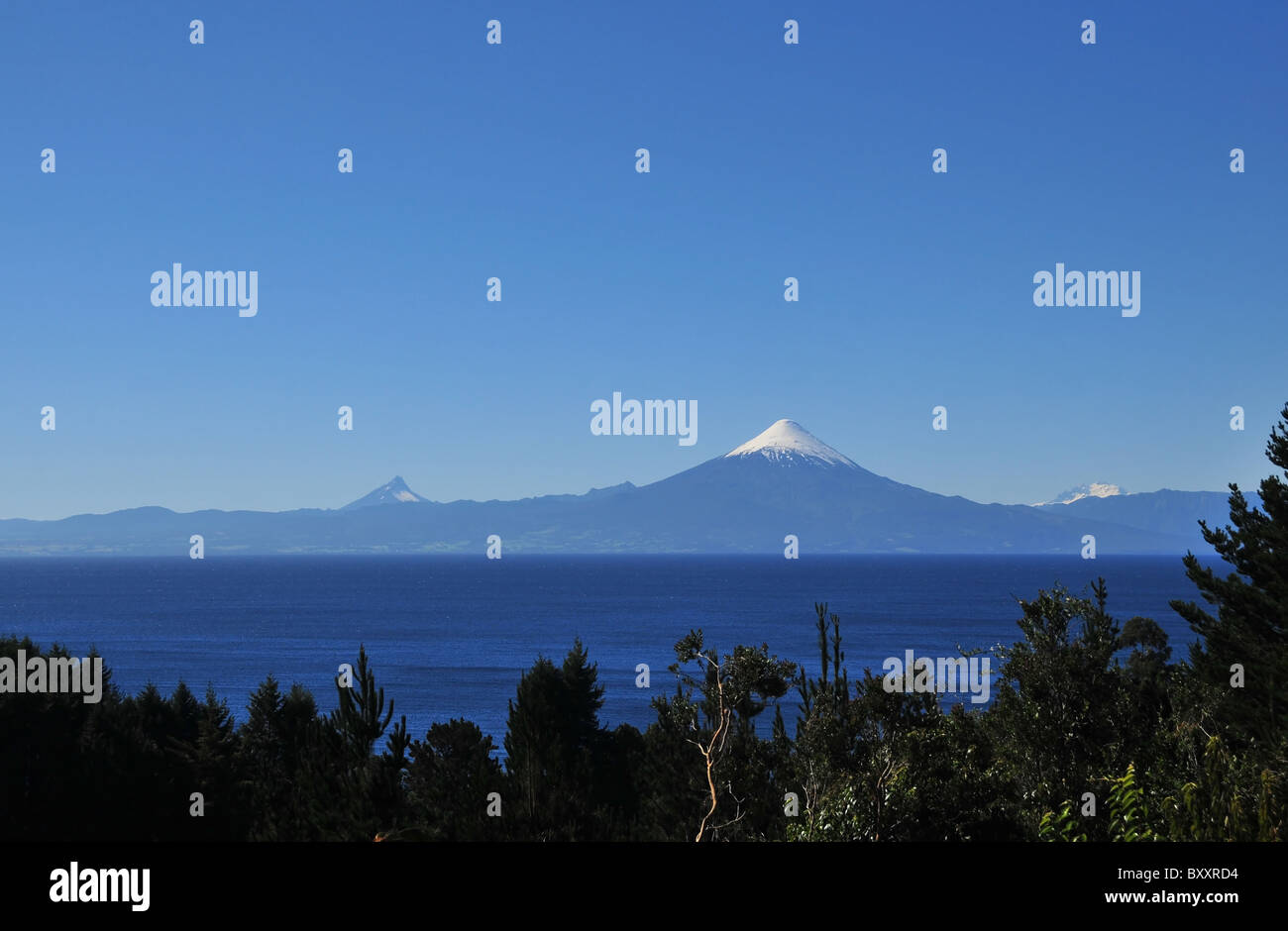 Dunkelblau erschossen, über Bäume, die symmetrische Kegel von Volcan Osorno, über das blaue Wasser des Sees Llanquihue, Anden, Chile Stockfoto