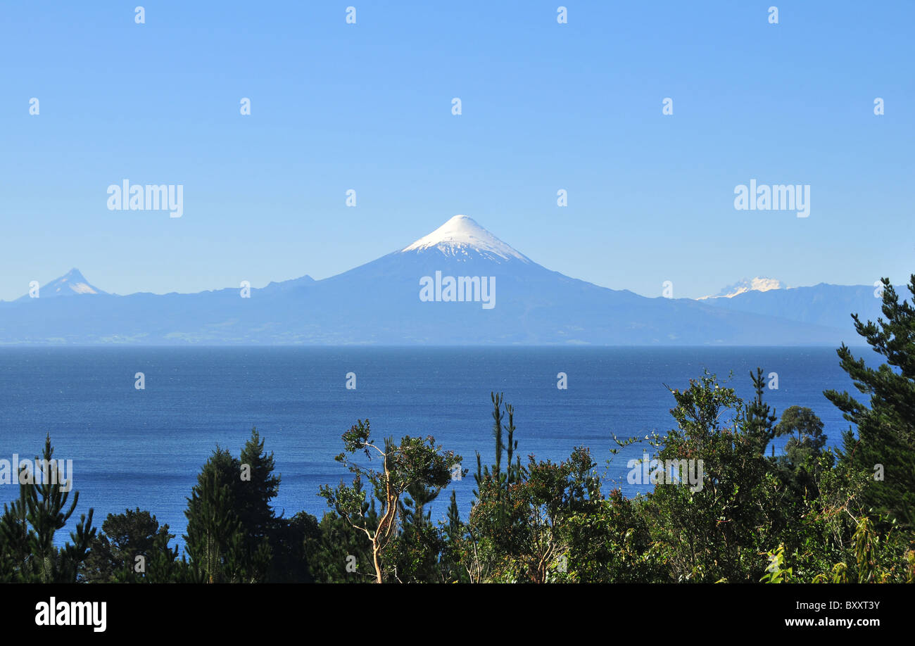 Blauer Himmelsblick über grüne Bäume, das blaue Wasser des Llanquihue Sees, mit Blick auf dem Eis Kegel des Volcan Osorno, Chile Stockfoto