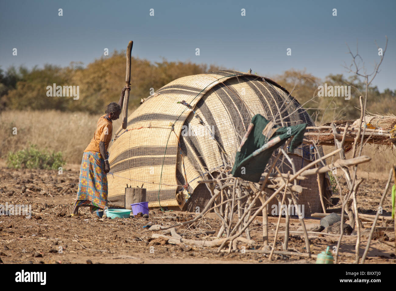 In saisonalen Dorf Bantagiri im Norden Burkina Faso Pfund Fulani Frauen Hirse außerhalb ein Haus aus Stroh Mat. Stockfoto