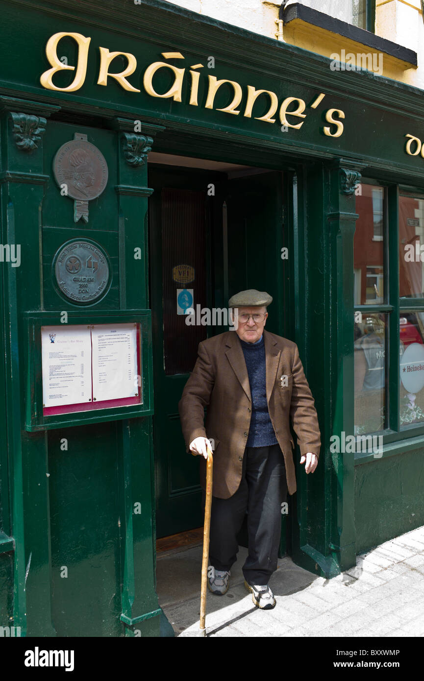Ältere lokale Ire mit Gehstock verlassen Grainne Bar in Mill Street, Timoleague, West Cork, Irland Stockfoto