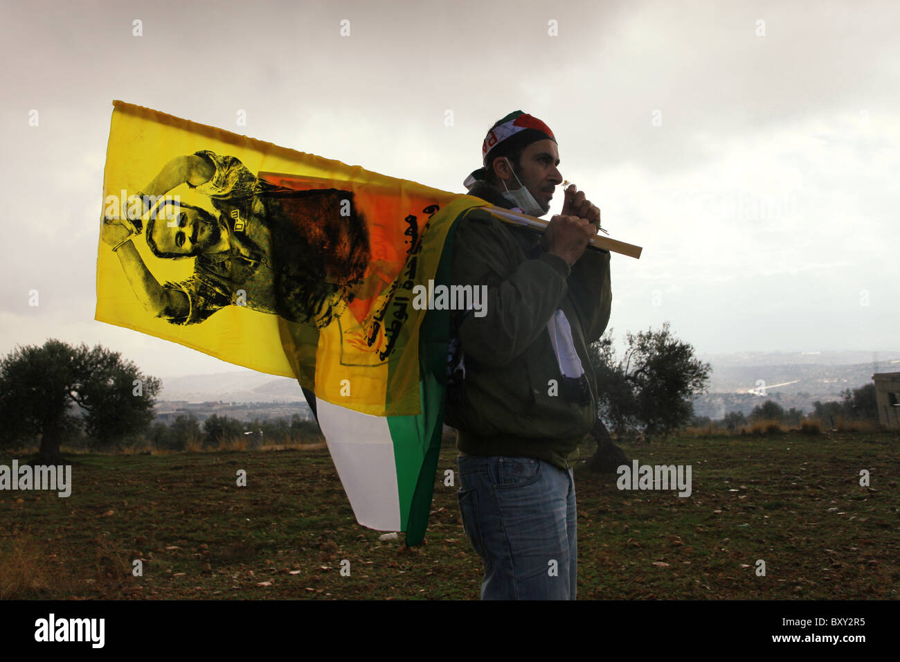 Palästinensischer Mann geht mit einer Flagge, die das Bild von Marwan Barghouti trägt, einer palästinensischen politischen Figur, die von Israel inhaftiert und als Anführer der ersten und zweiten Intifadas angesehen wird, während einer Kundgebung, die sechs Jahre lang gegen Israels umstrittene Barriere im Dorf Bilin Israel stattfand Stockfoto