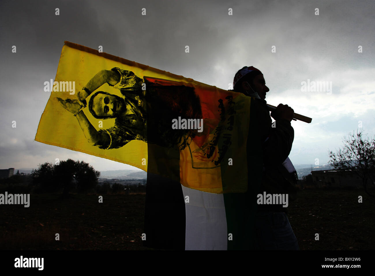 Der palästinensische Mann läuft mit einer Flagge, die das Bild von Marwan Barghouti trägt, einer palästinensischen politischen Figur, die von Israel gefangen gehalten und während einer Kundgebung, die sechs Jahre lang an Demonstrationen gegen Israels umstrittene Barriere stattfand, im Dorf Bilin Israel im Westjordanland als Führer der ersten und zweiten Intifadas angesehen wird Stockfoto