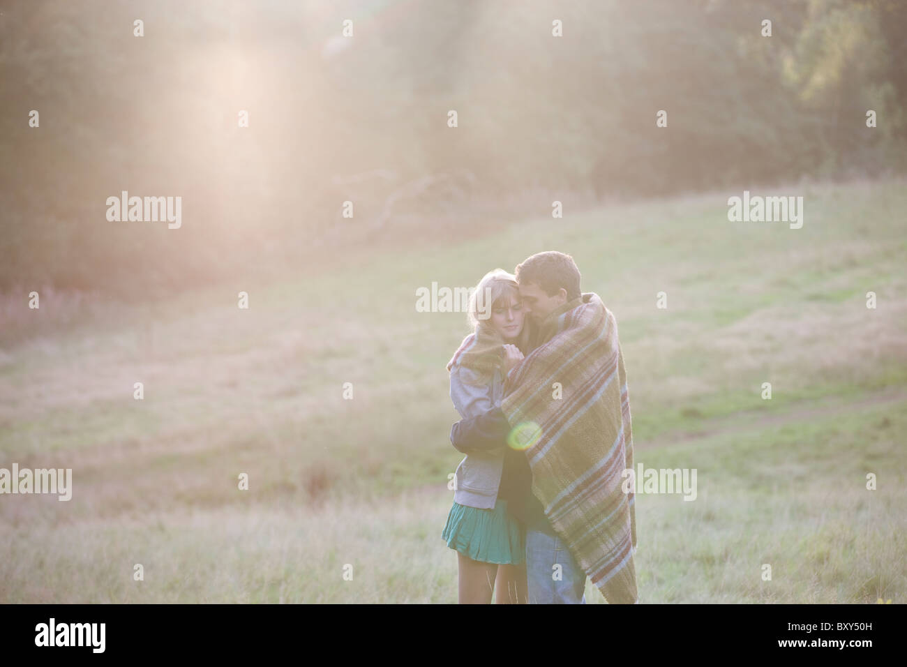 Ein junges Paar umarmt im Freien, in eine Decke gehüllt Stockfoto