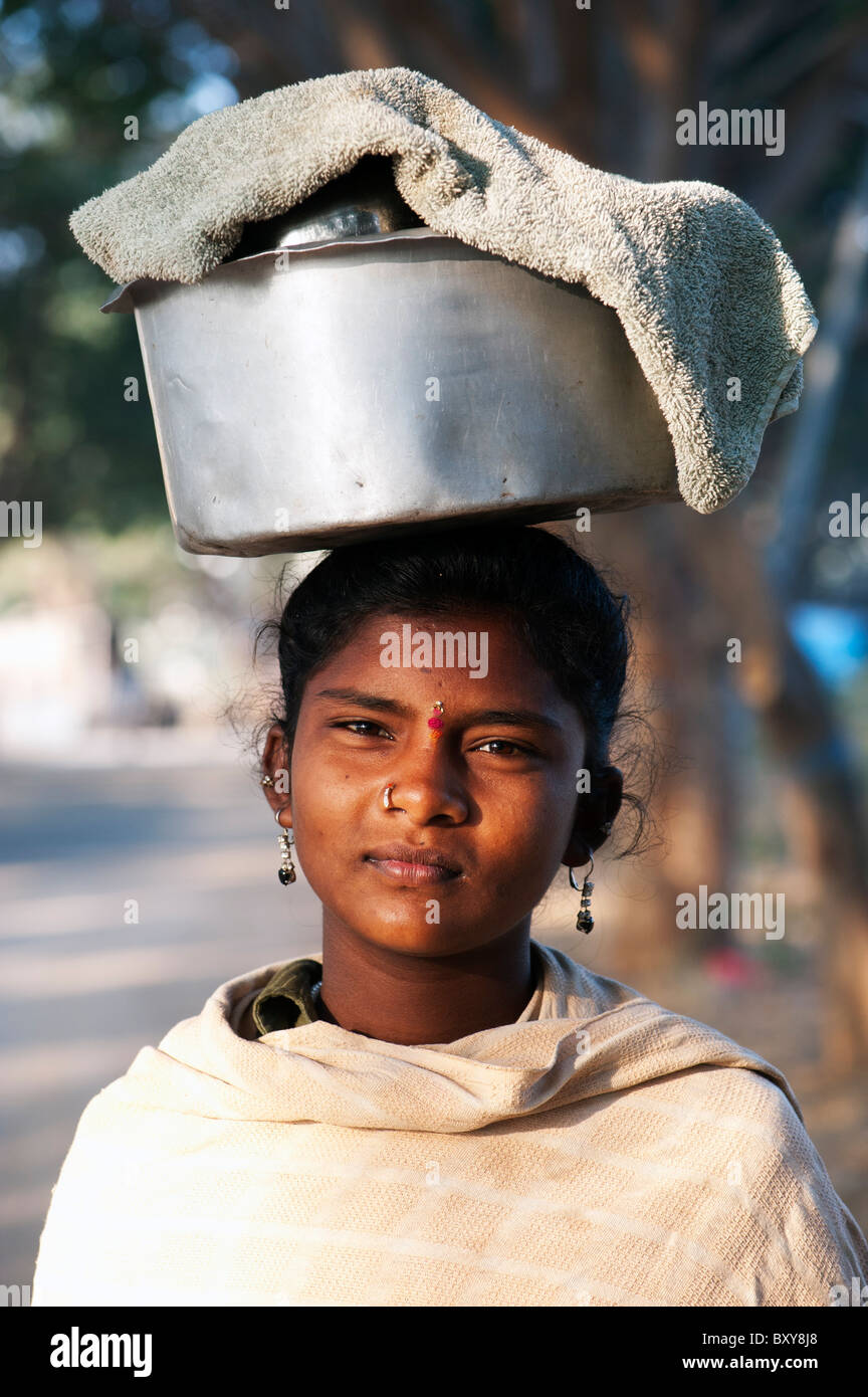 Armen niedrigere Kaste indischen TeenagerMädchen tragen einen Topf mit Reis auf den Kopf