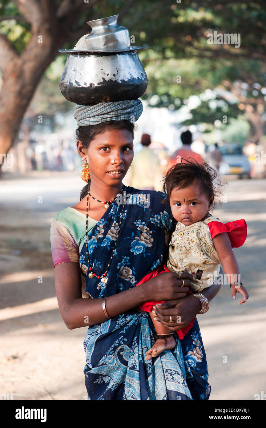 Armen niedrigere Kaste indische Frau mit Baby mit einem Topf Reis auf dem Kopf. Andhra Pradesh, Indien Stockfoto