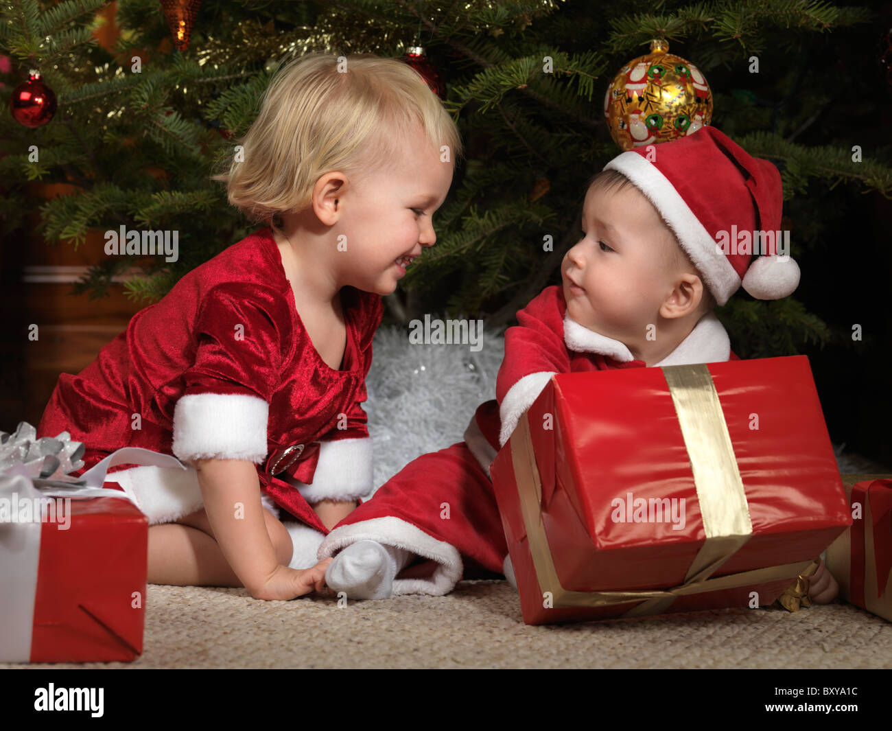 Lizenz erhältlich unter MaximImages.com – der acht Monate alte Junge möchte seine Weihnachtsgeschenke nicht mit einem zweijährigen Mädchen teilen Stockfoto