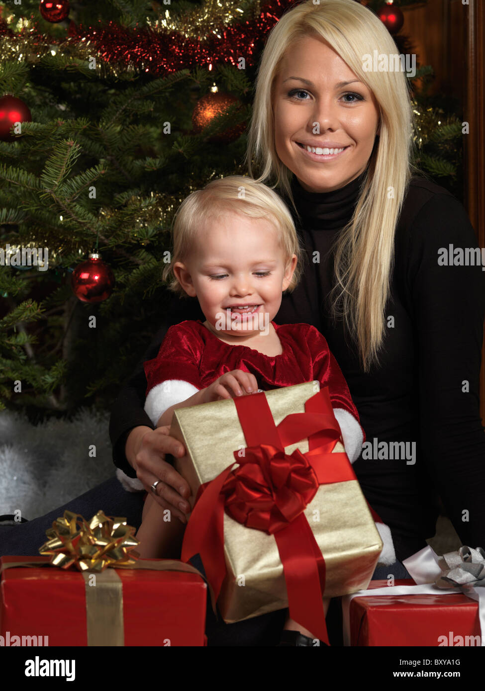 Porträt einer Mutter und ihrer Tochter Eröffnung präsentiert unter einem Weihnachtsbaum Stockfoto