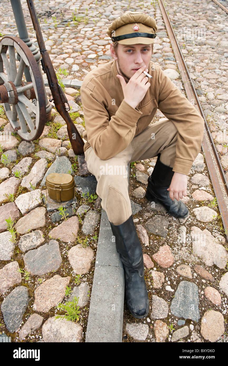 Soldat in Uniform des ersten Weltkrieges, hinsetzen, ruht auf dem Bürgersteig und Rauchen. Kostüm Accord Zeiten Weltkrieg I. Foto Stockfoto