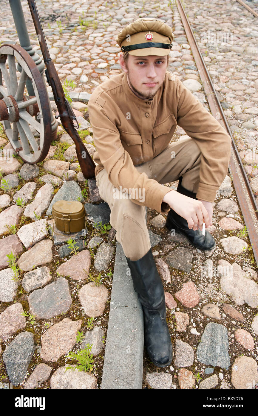 Soldat in Uniform des ersten Weltkrieges, hinsetzen, ruht auf dem Bürgersteig und Rauchen. Kostüm Accord Zeiten Weltkrieg I. Foto Stockfoto