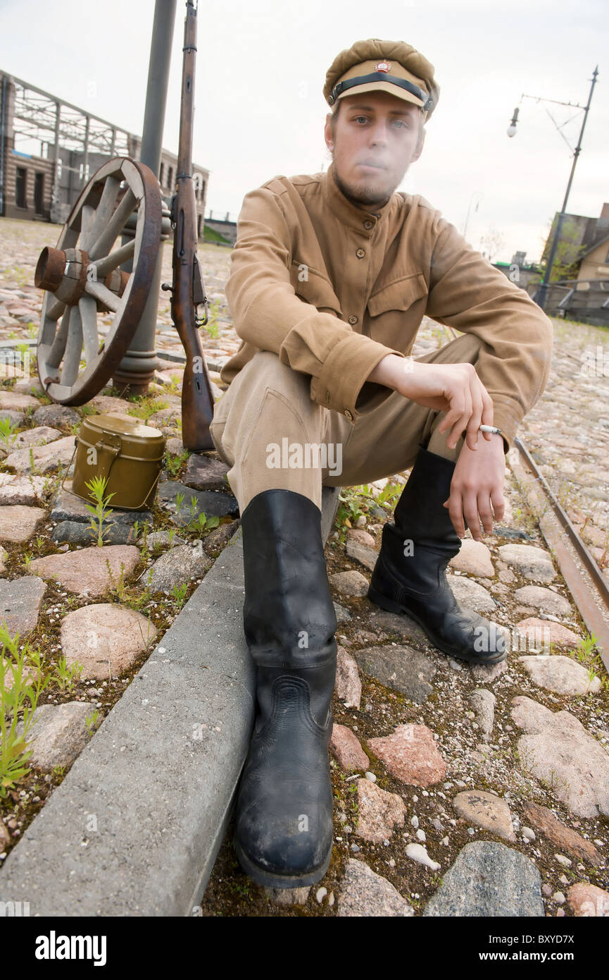Soldat in Uniform des ersten Weltkrieges, hinsetzen, ruht auf dem Bürgersteig und Rauchen. Kostüm Accord Zeiten Weltkrieg I. Foto Stockfoto
