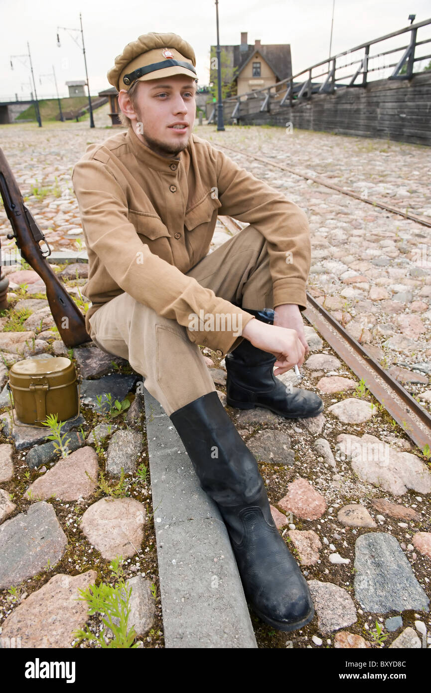 Soldat in Uniform des ersten Weltkrieges, hinsetzen, ruht auf dem Bürgersteig und Rauchen. Kostüm Accord Zeiten Weltkrieg I. Foto Stockfoto