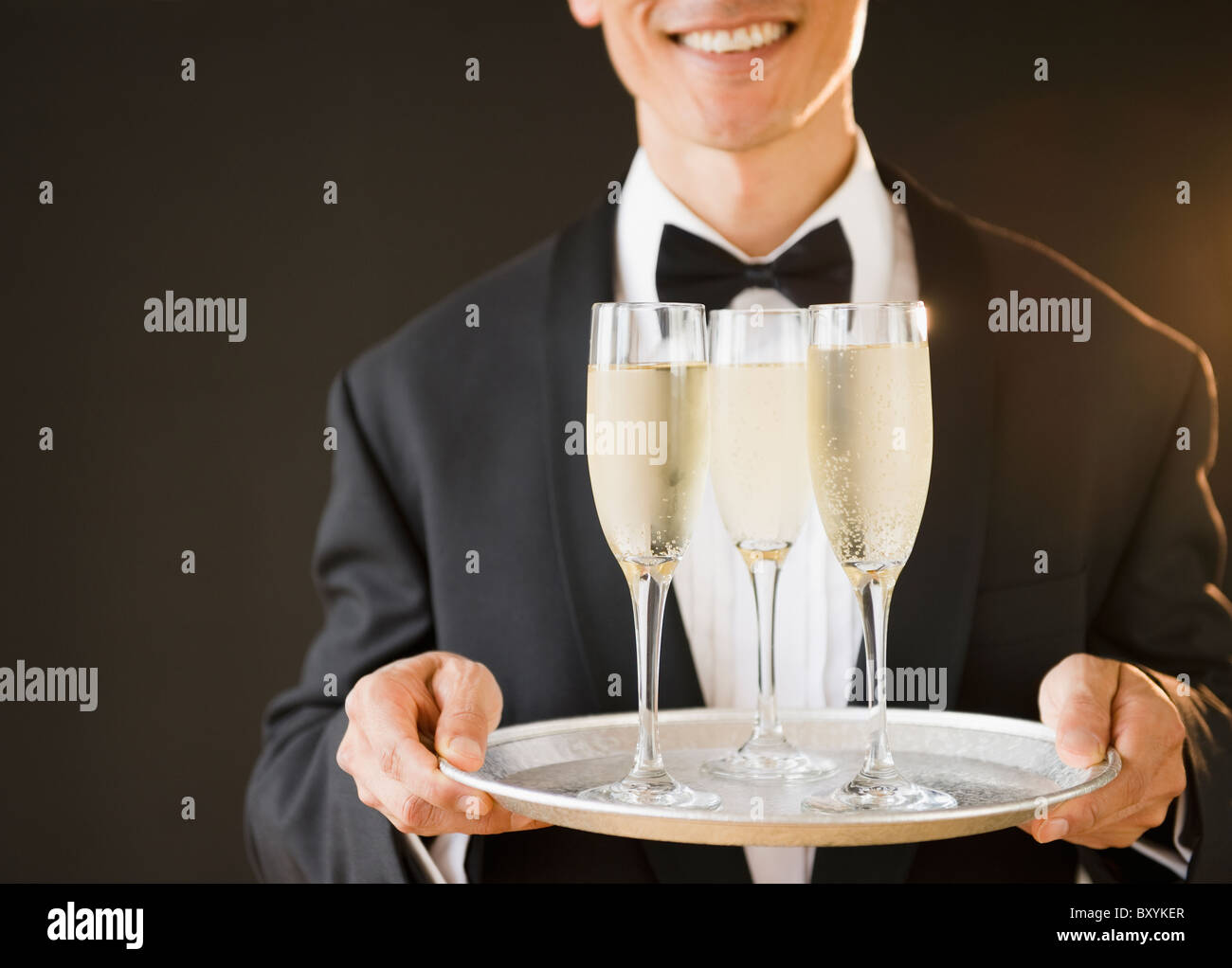 Kellner tragen Fliege und Holding-Tablett mit Champagner-Flöten, Studio gedreht Stockfoto