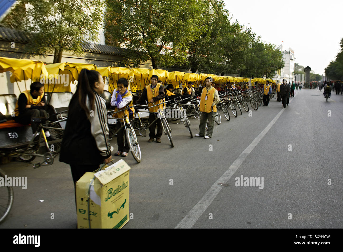 CHINA, BEIJING: Rikscha-Fahrer mit gelber überdachte Fahrradrikschas warten auf Kunden im Hutong-Viertel von Peking. Stockfoto
