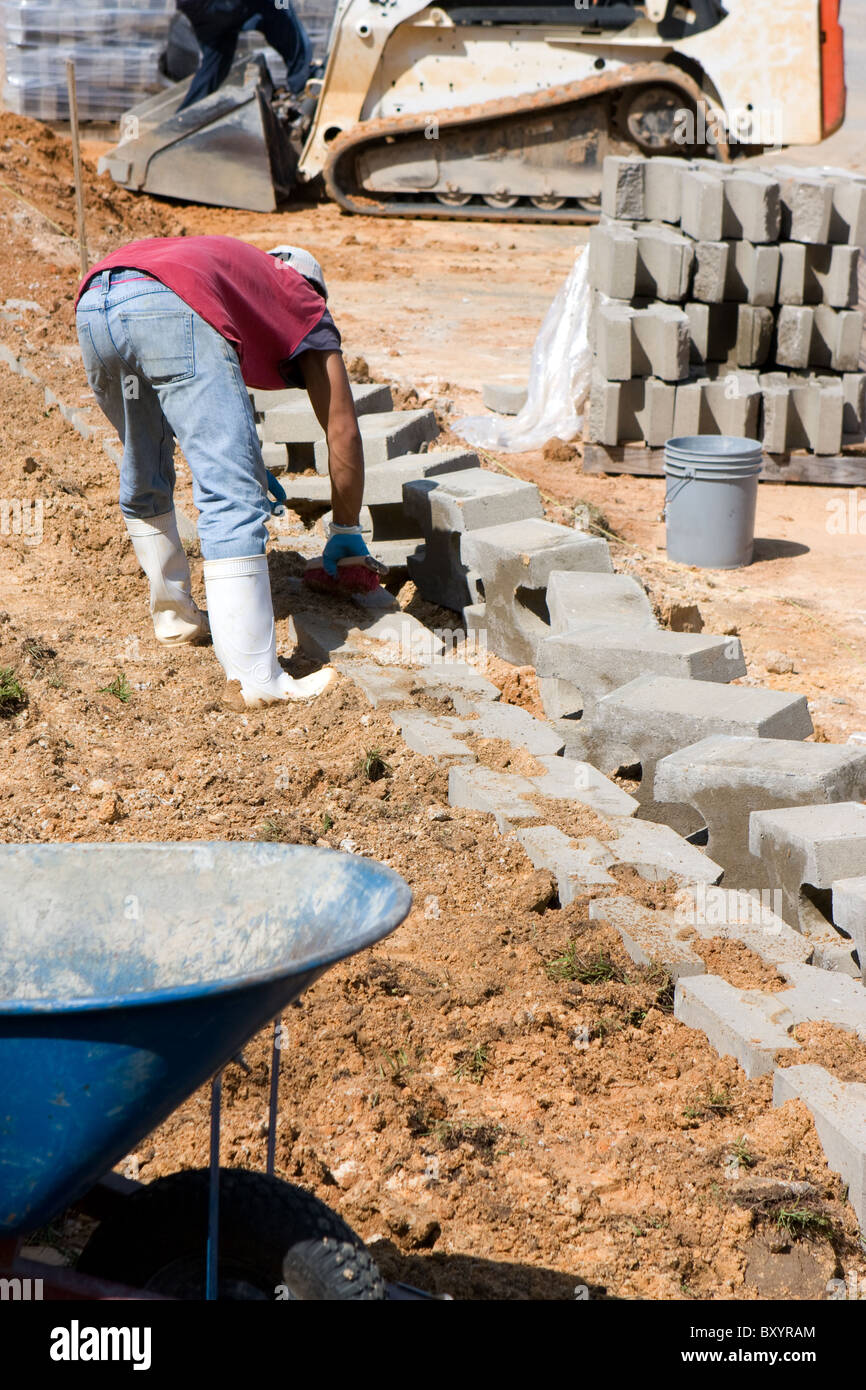 Ein Bauarbeiter legt Betonblöcke für eine Stützmauer. Stockfoto