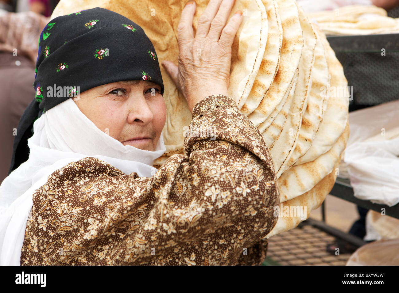 Syrische Frau im Kopftuch tragen frisch gebackene Fladenbrote außerhalb einer Backstreet-Bäckerei in der alten Stadt von Damaskus, Syrien Stockfoto