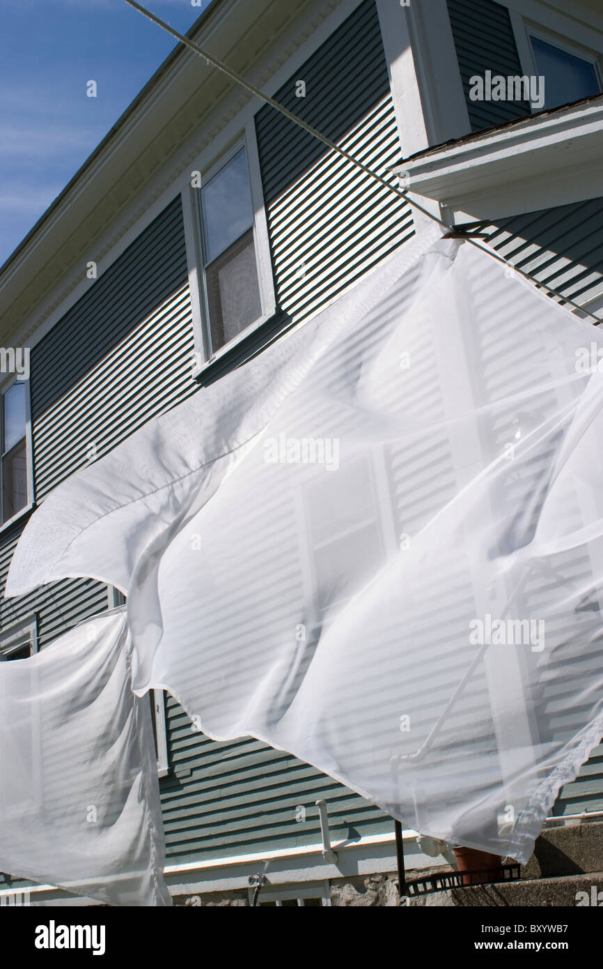 Gardinen Welle in der Brise an einem sonnigen Tag in der Seite Hof eines Hauses grauen Schindeln Trocknen. Stockfoto