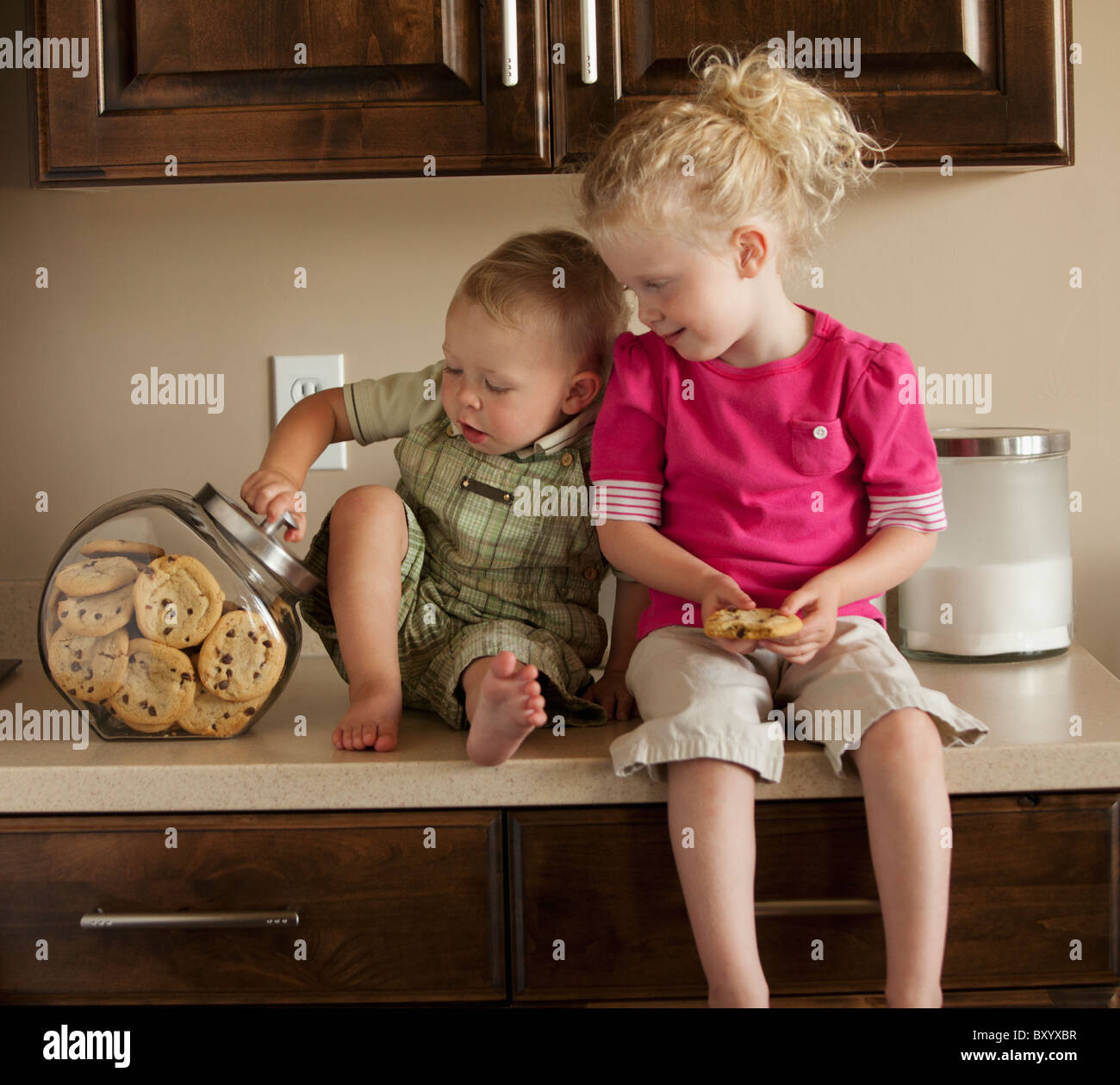 Jungen und Mädchen teilen Cookies auf Küchenarbeitsplatte Stockfoto