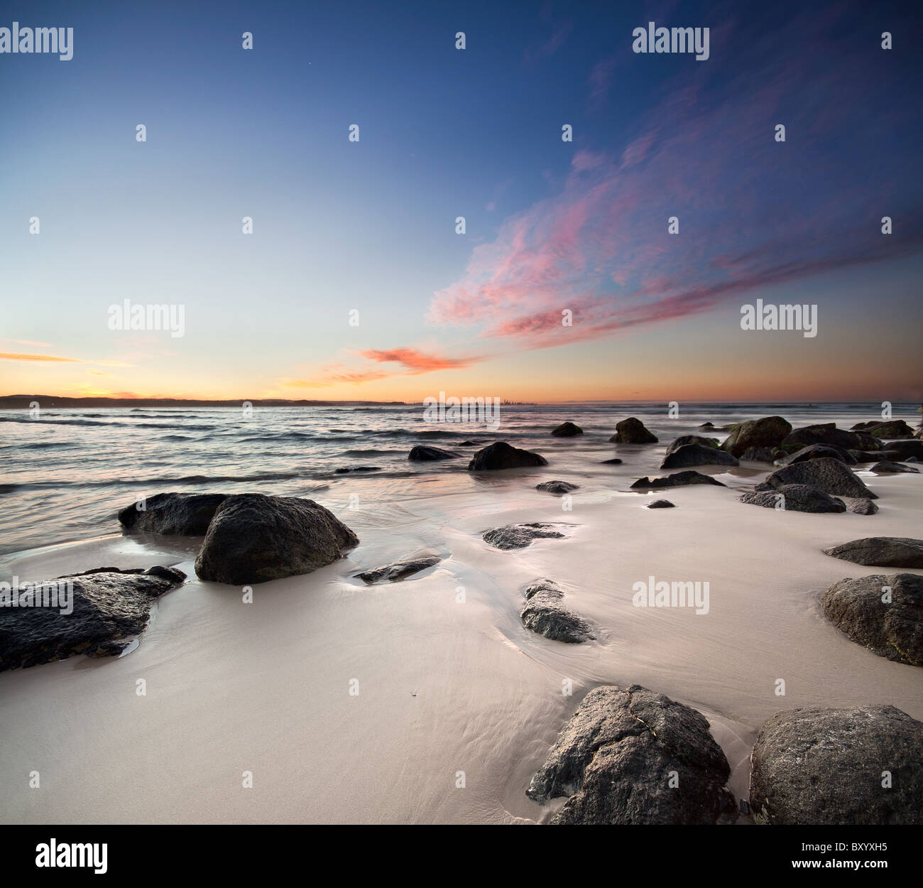 Felsen am Strand mit roten Wolken auf ein quadratisches format Stockfoto