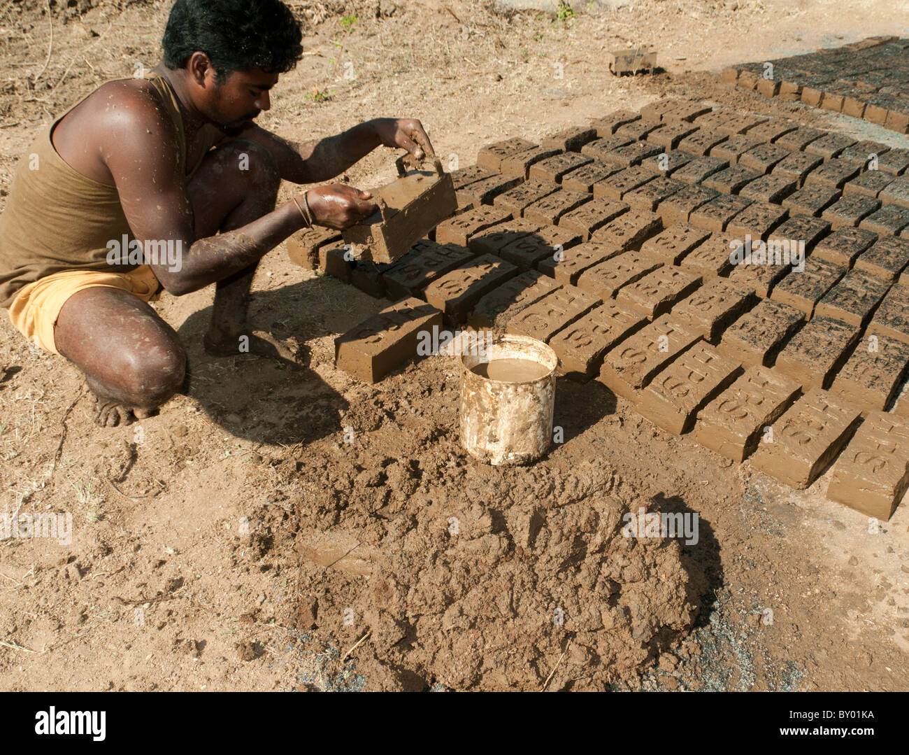Ein Mann, der die Ziegel von hand getrocknet, dann in der Sonne In Indien Stockfoto